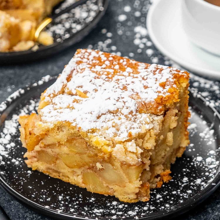 a slice of apple pie cake on a black plate.