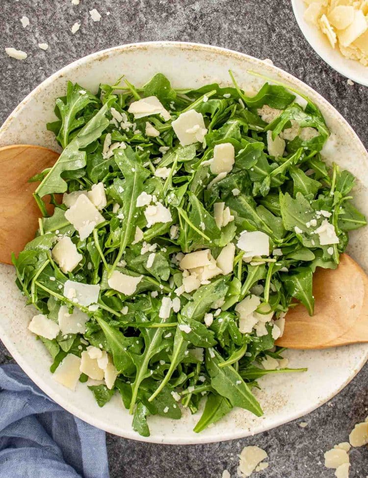 Top view of arugula salad with shaved Parmesan and lemon dressing, fresh, vibrant, and perfect for pairing with any meal.