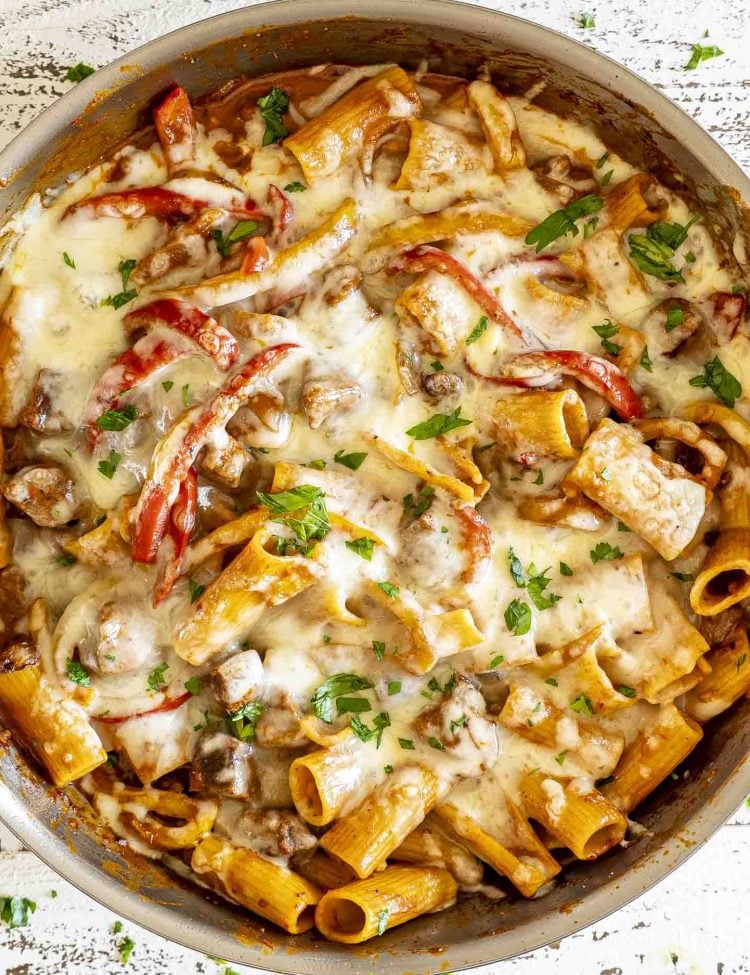 Overhead shot of bubbling beef and pepper pasta skillet fresh from broiler, melted mozzarella golden and sprinkled with parsley.