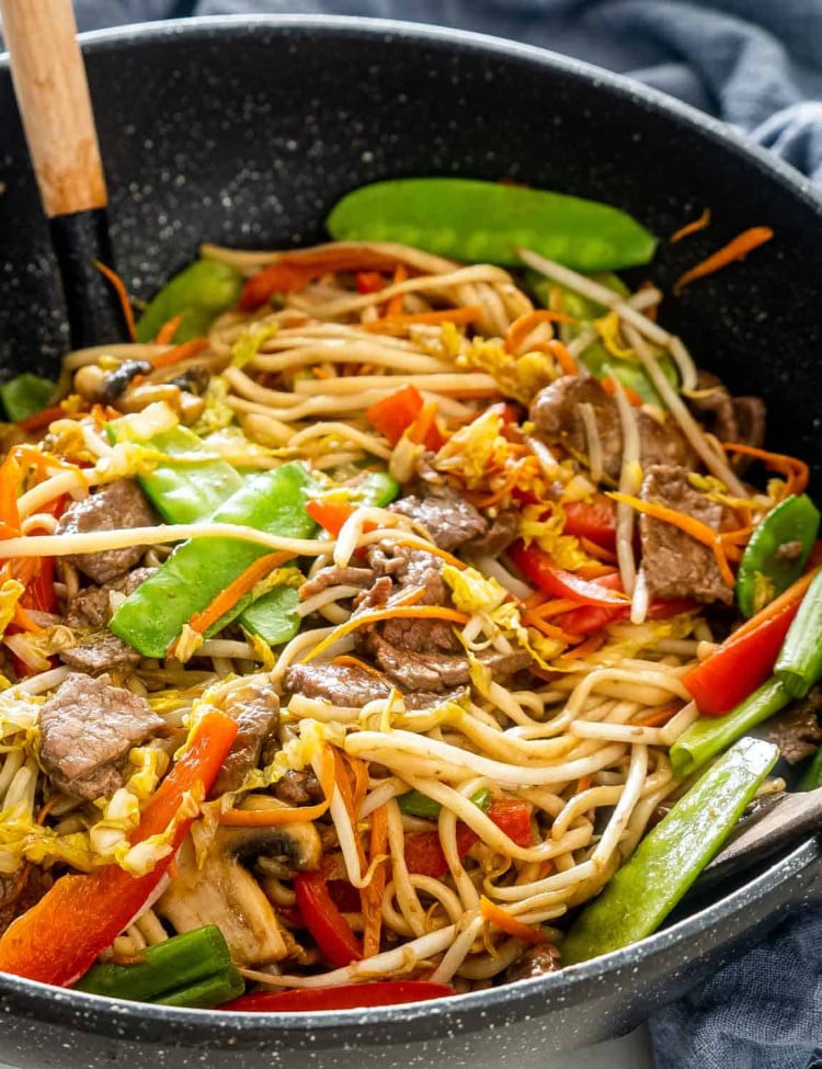 beef lo mein in a black wok.