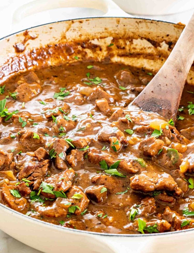 beef tips with gravy in a braiser garnished with parsley.