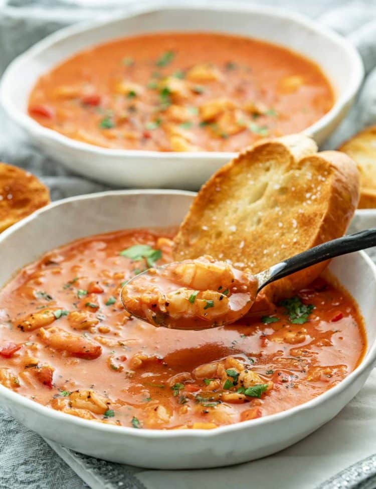 Spoonful of creamy Brazilian shrimp soup with rice, served in a white bowl with toasted bread.