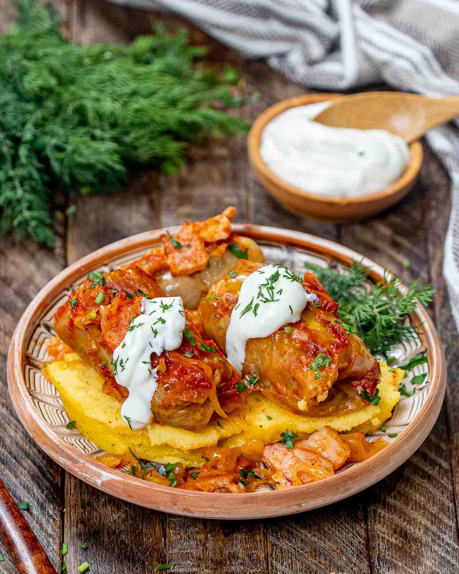 two cabbage rolls on polenta and garnished with sour cream.