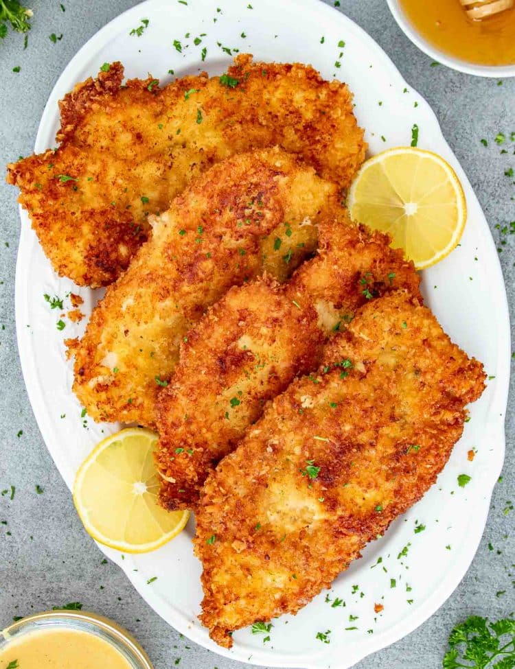 a few chicken cutlets on a white platter.