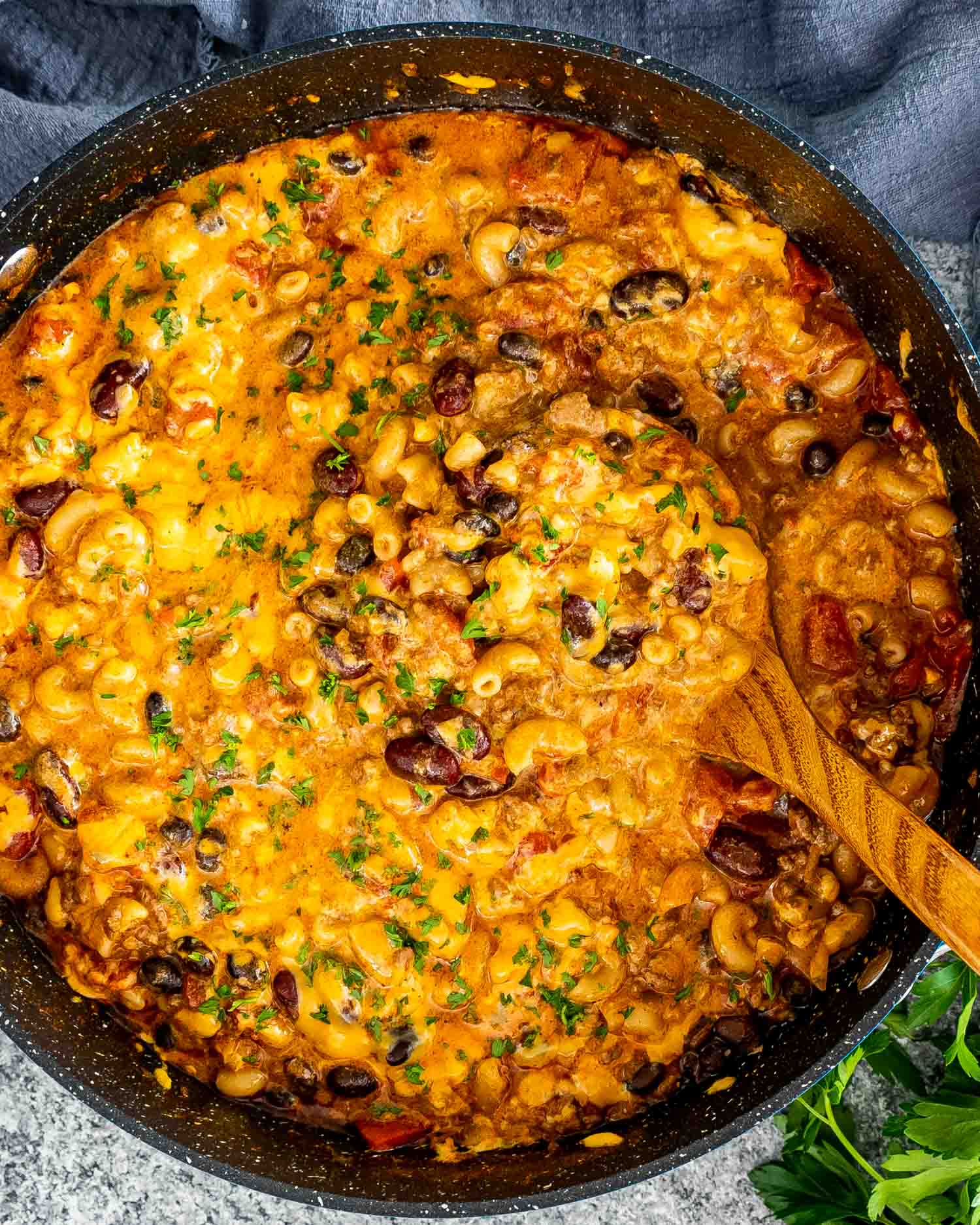freshly made chili mac and cheese in a pot with a wooden ladle in it.