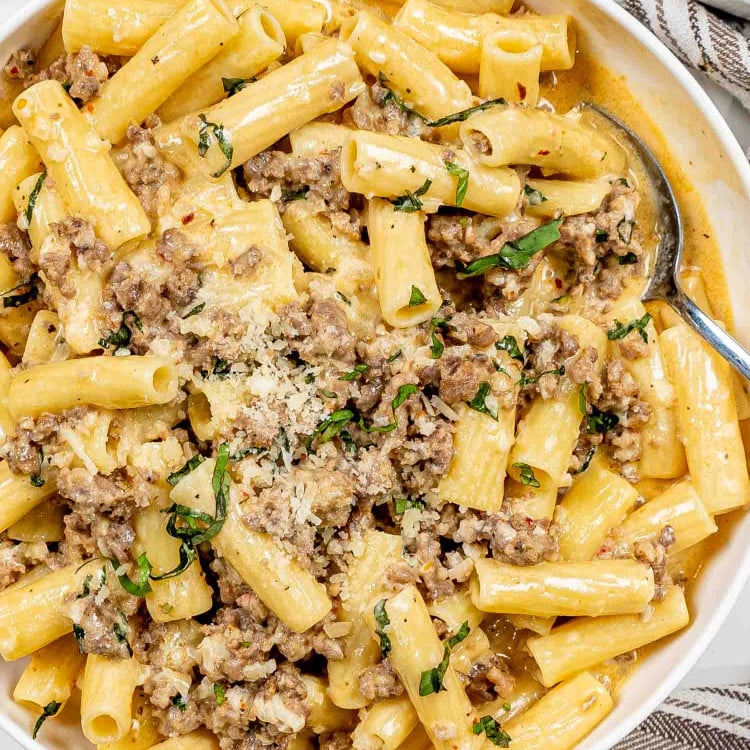 creamy italian sausage pasta in a white serving bowl.