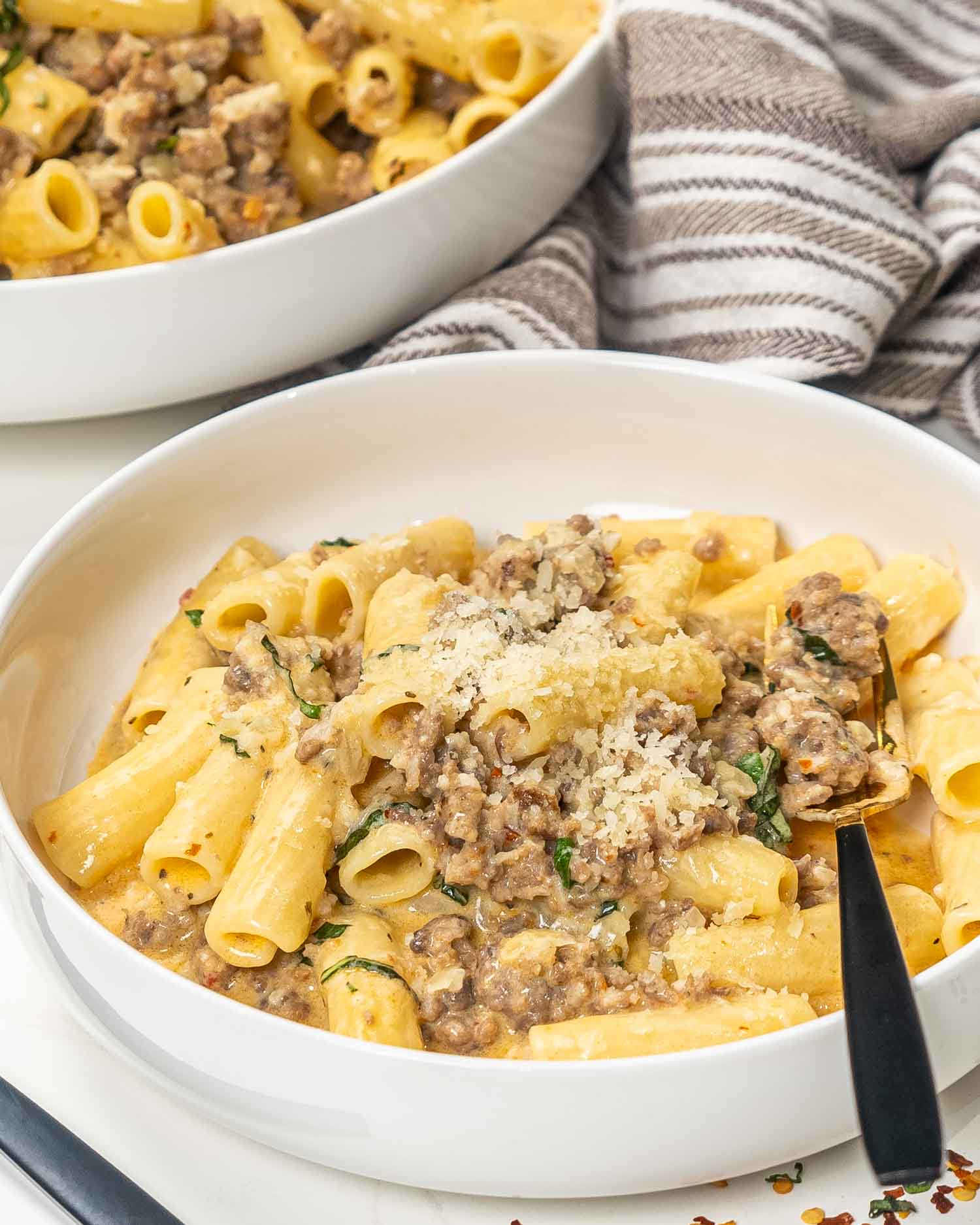a serving of creamy italian sausage pasta in a white bowl.