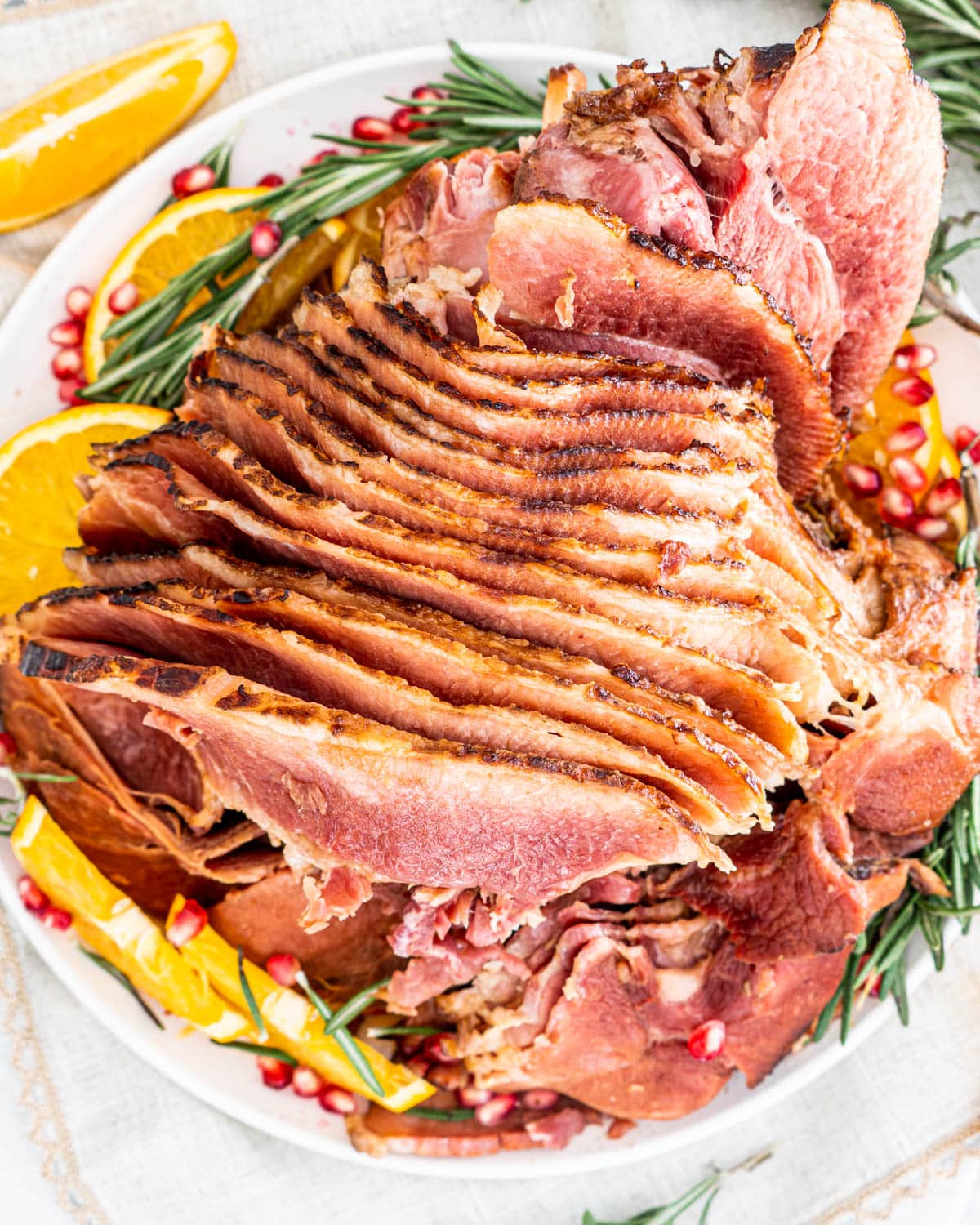 overhead show of Crockpot Brown Sugar Cola Glazed Ham on a platter garnished with oranges and pomegranates seeds