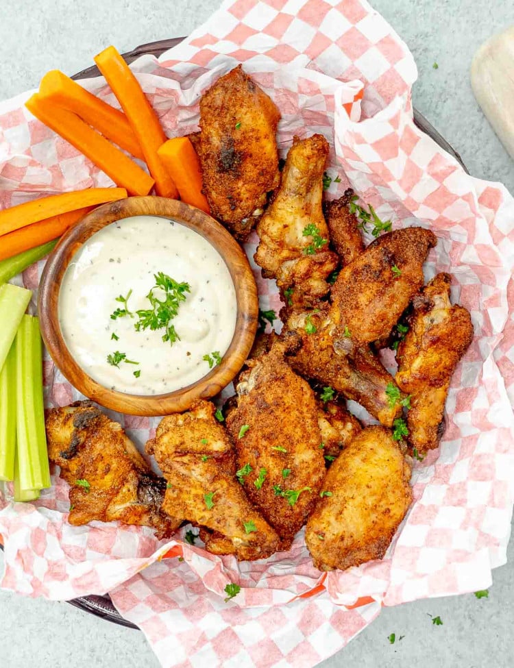 dry rub wings in a basket with ranch dressing, carrots, and celery.