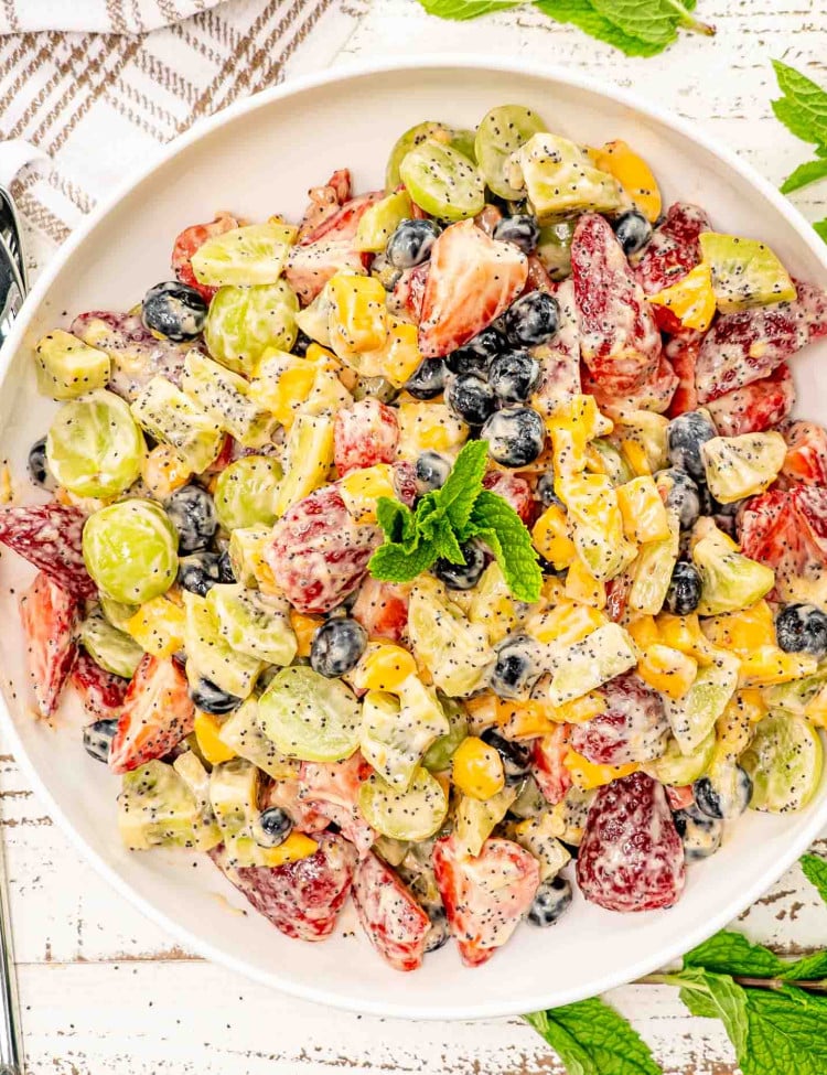 fruit salad with creamy poppy seed dressing in a white bowl.
