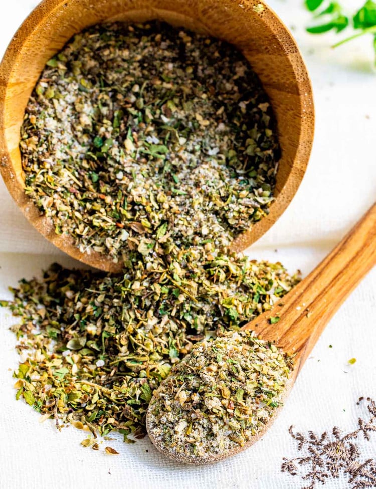 greek seasoning in a wooden bowl with a tiny wooden spoon.