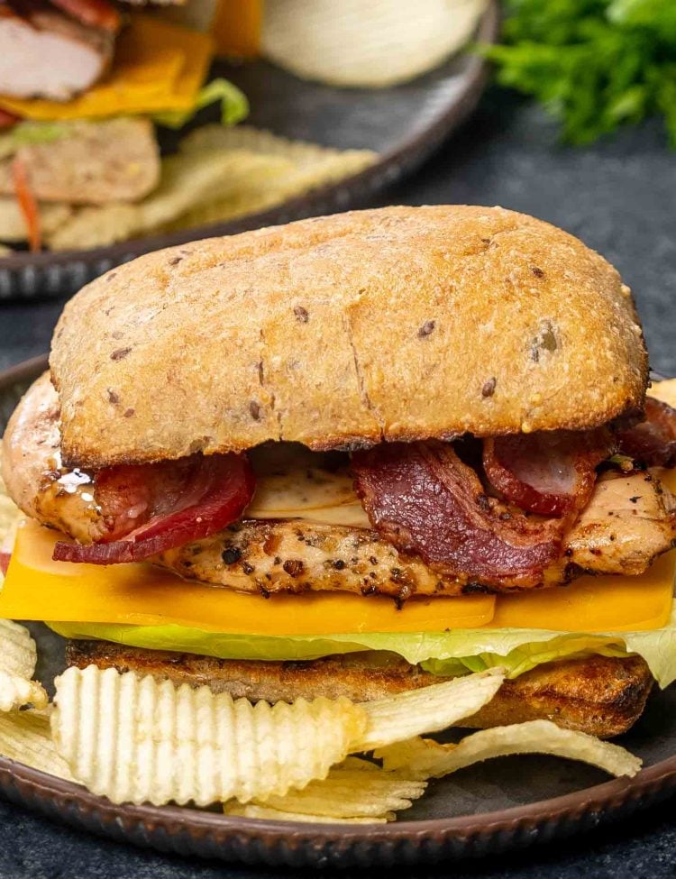 a grilled chicken sandwich a plate with potato chips.