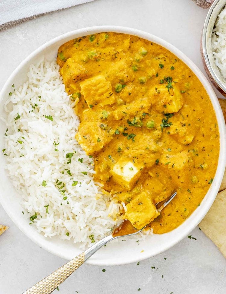 Bowl of matar paneer served alongside white basmati rice, perfect for scooping with naan or roti.