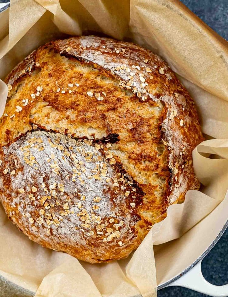 freshly baked no knead honey oat bread in a dutch oven.