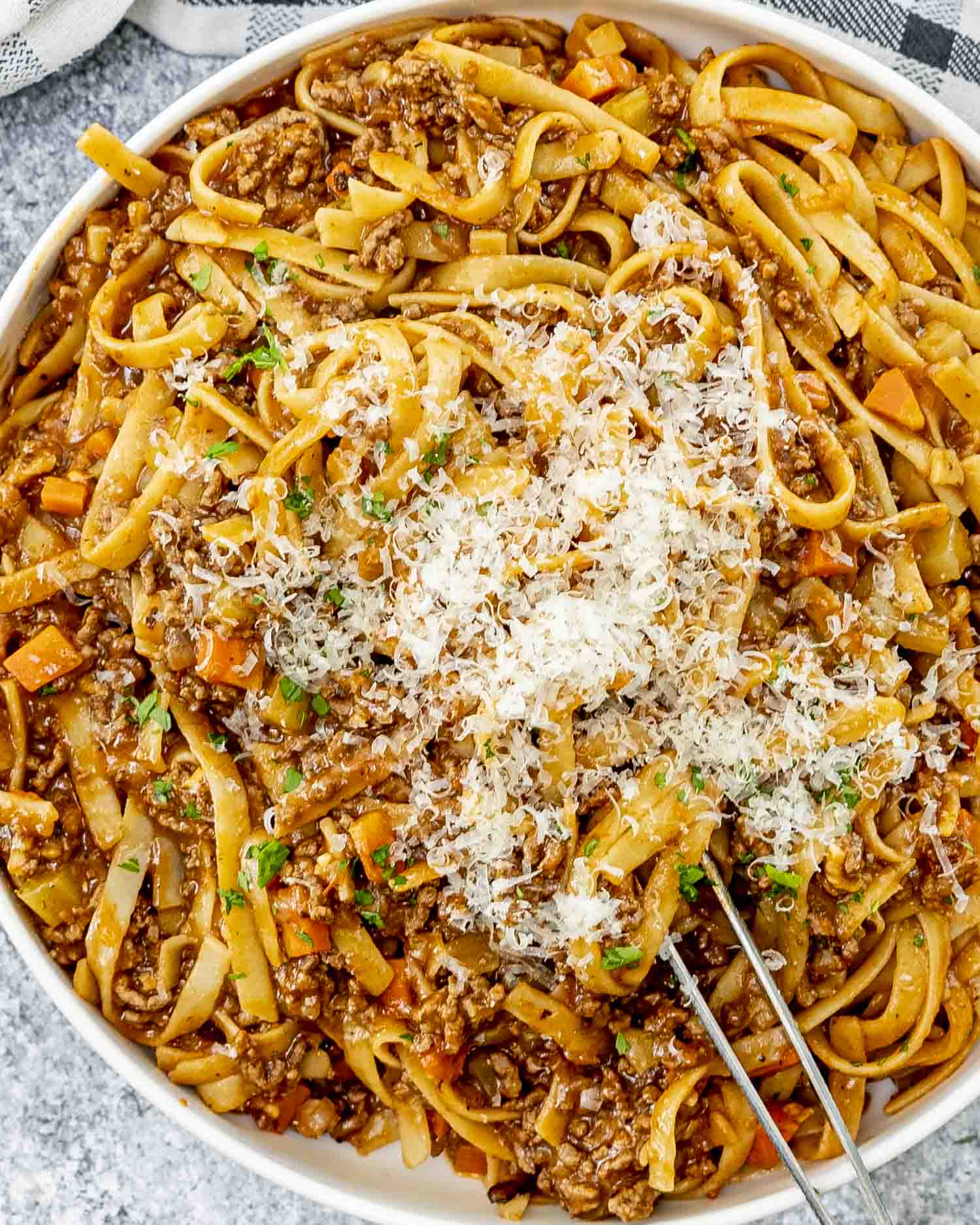 beef ragu pasta garnished with a bit of parsley in a white serving bowl.