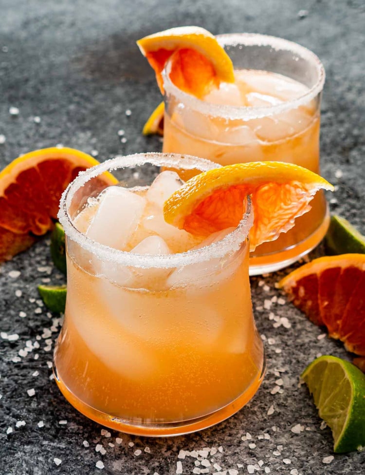 two glasses filled with paloma and garnished with grapefruit slice.