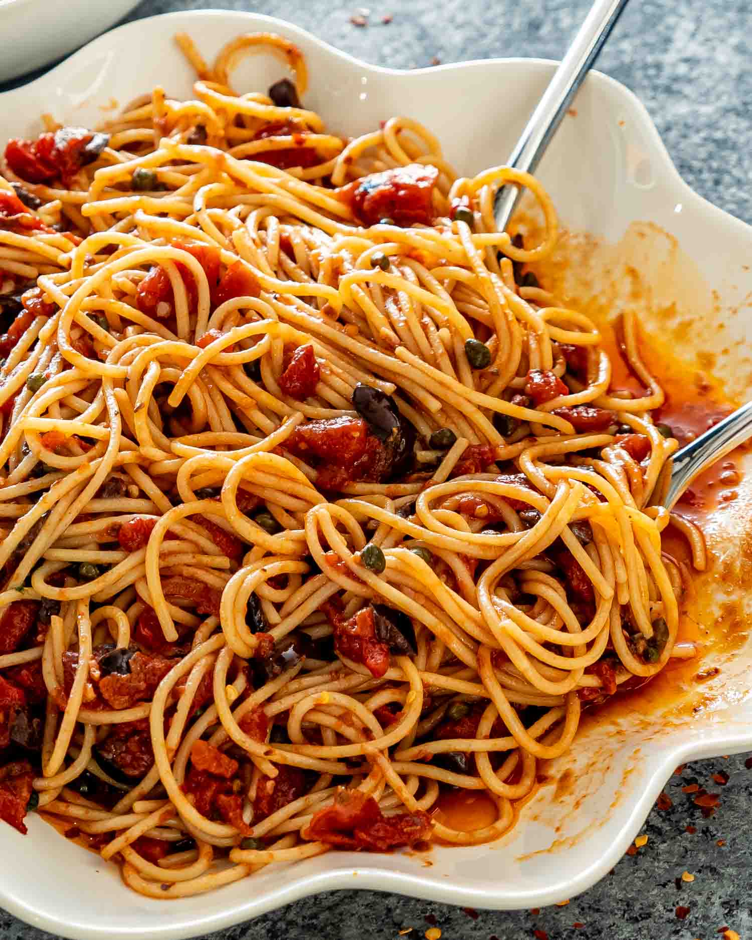 pasta puttanesca in a white serving bowl.