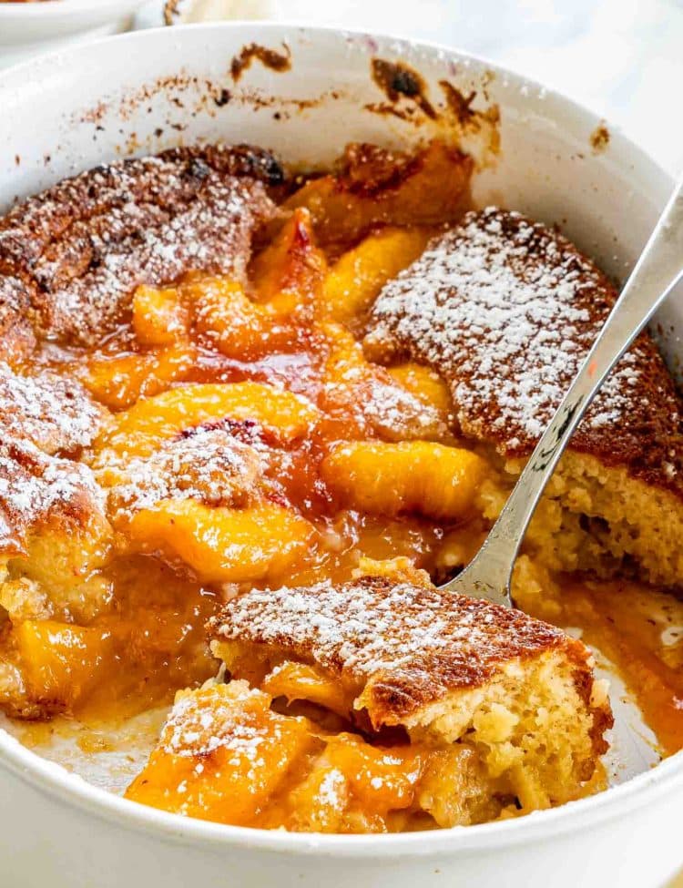 freshly made peach cobbler in a white oval baking dish.