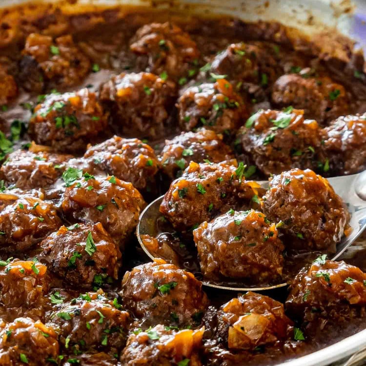 salisbury steak meatballs with gravy in a skillet garnished with parsley.