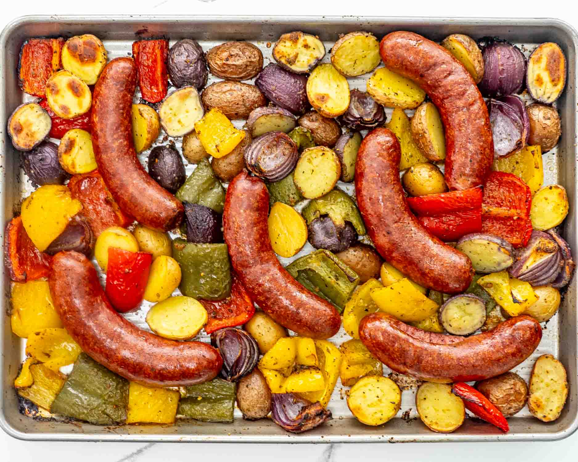 process shots showing how to make sausage and potato sheet pan dinner.