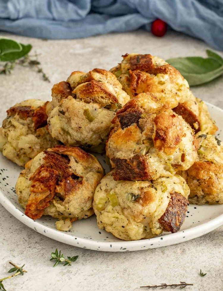 Close-up of baked stuffing balls on a speckled plate, highlighting crisp texture, golden crust, and soft herby interior.