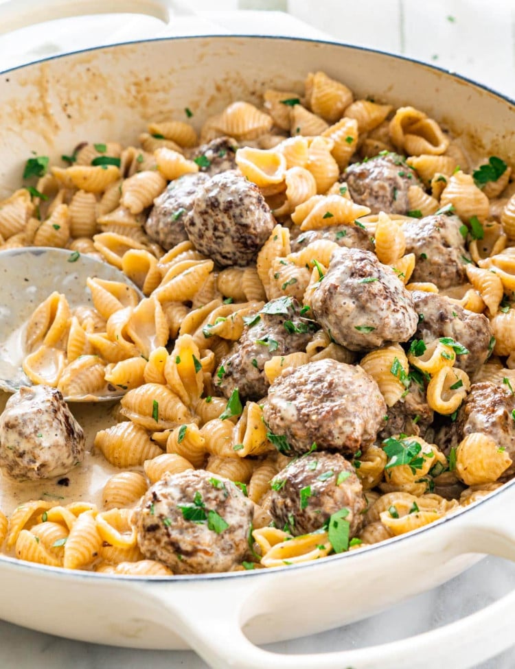 side close up shot of swedish meatball pasta in a beige braised garnished with parsley