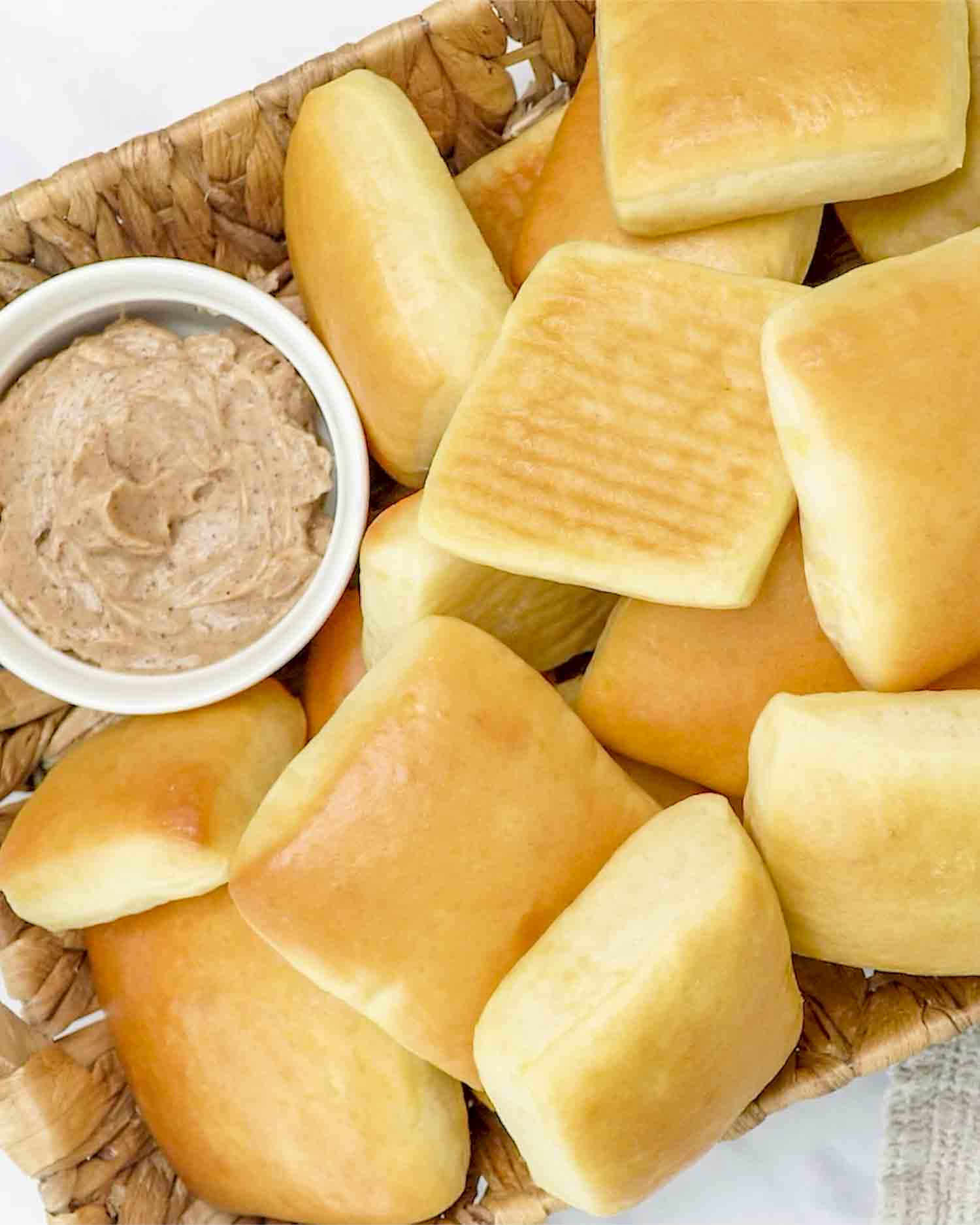 freshly baked texas roadhouse rolls in a basket along honey cinnamon butter in a little bowl.