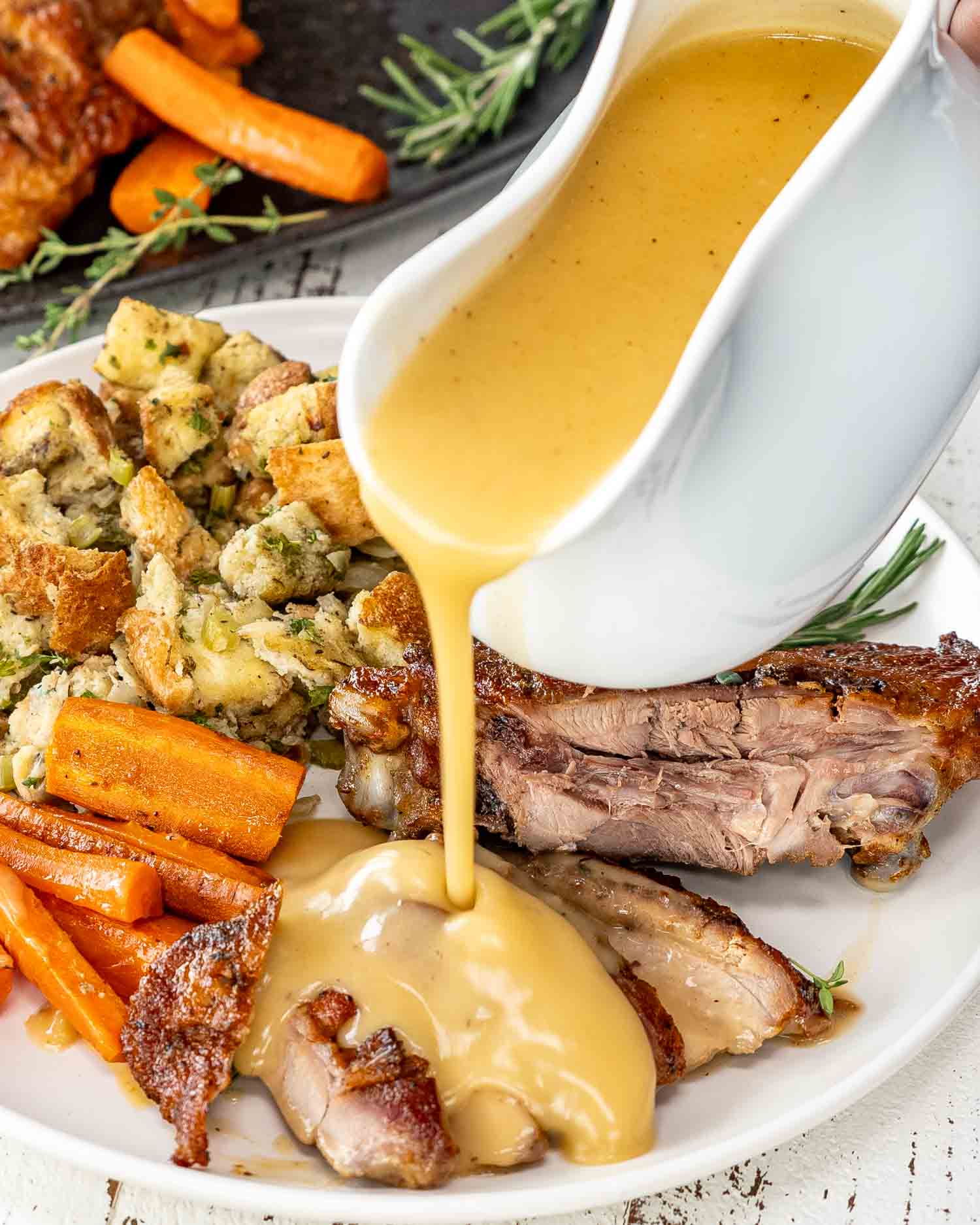 a hand holding a gravy bowl and pouring over turkey.